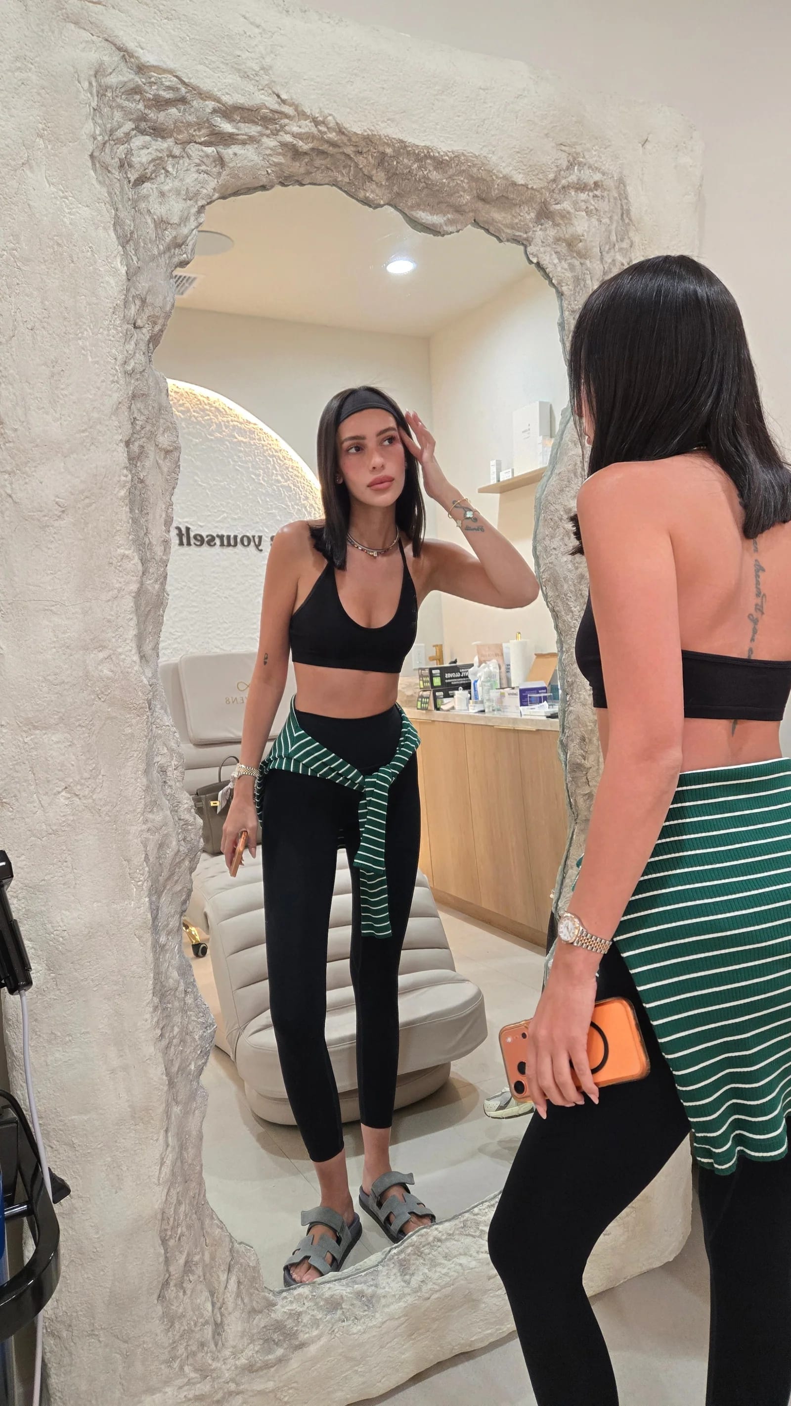 A client checking her skin in the rock-framed mirror of a Rejuven8 treatment room