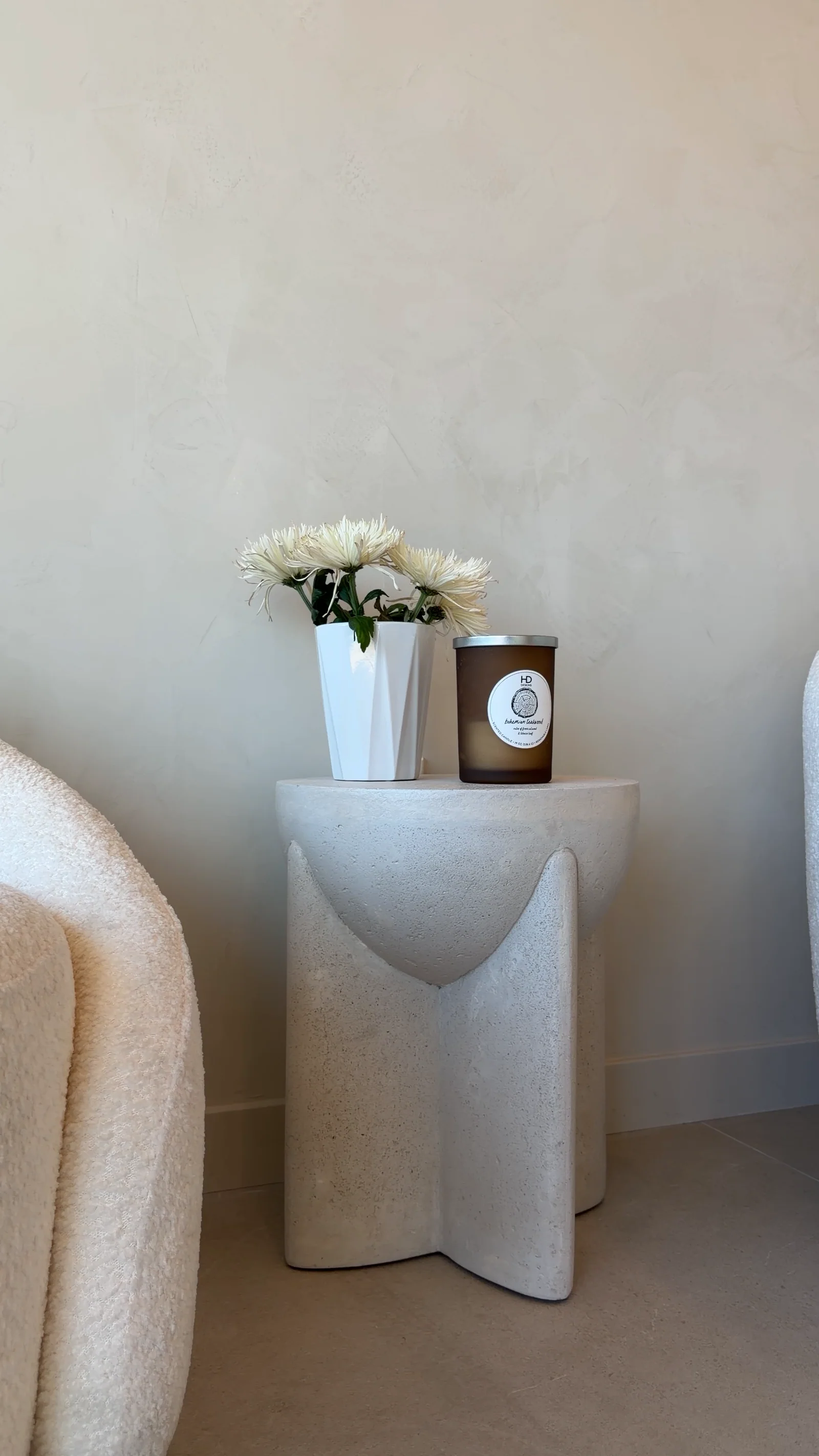 White flowers and a candle on a sculpted stone side table in the Rejuven8 lobby