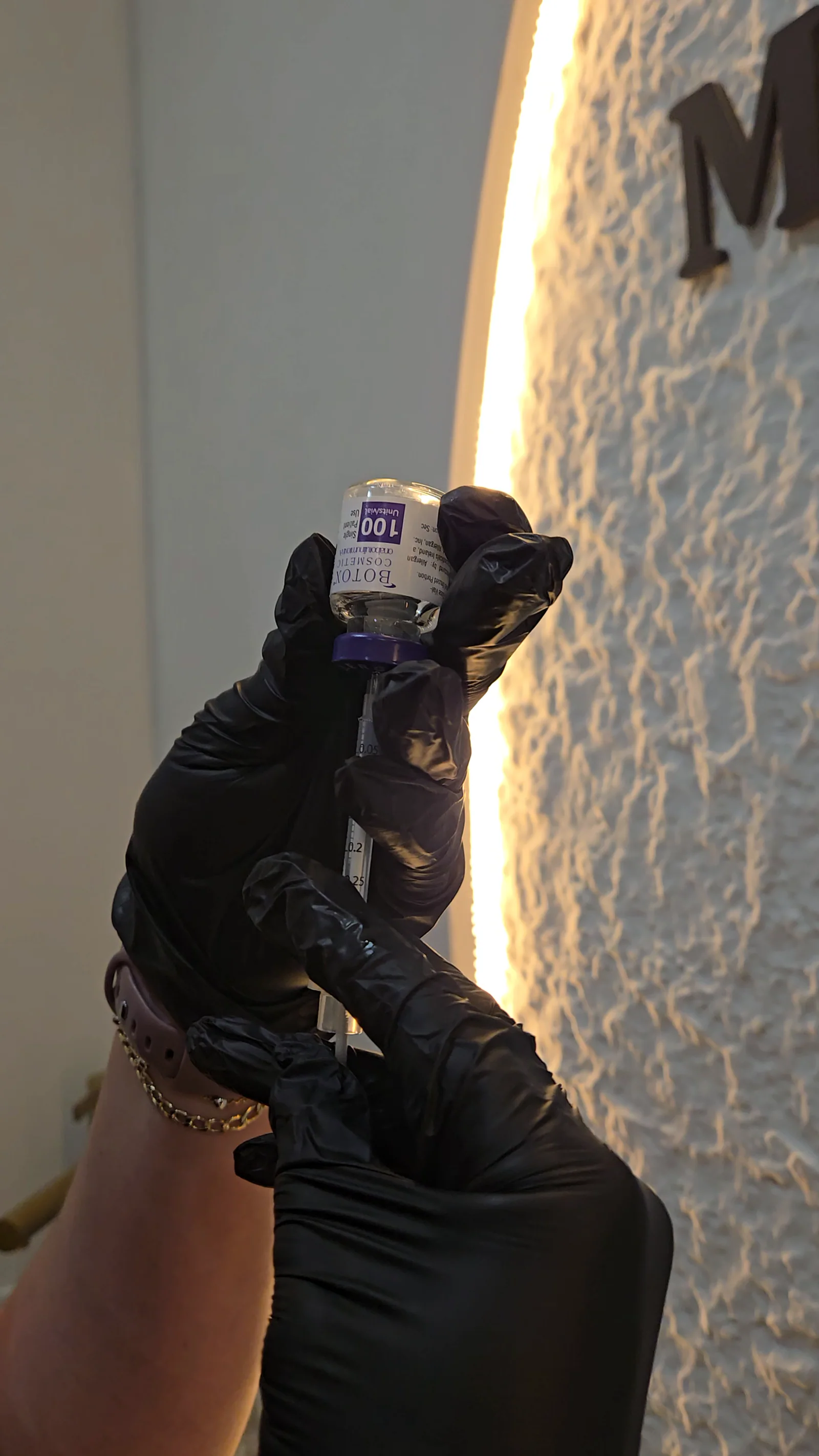 A gloved hand holds up a vial of Botox Cosmetic in a Rejuven8 treatment room